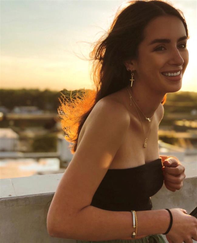 Young woman smiling  and moving to frame right, the sun is setting behind her