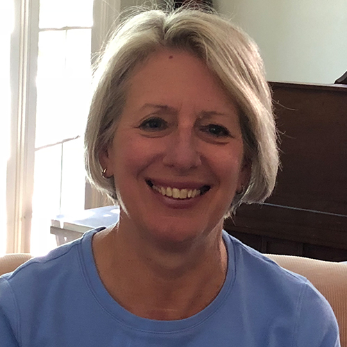 Smiling woman with short Grey hair wearing a blue shirt