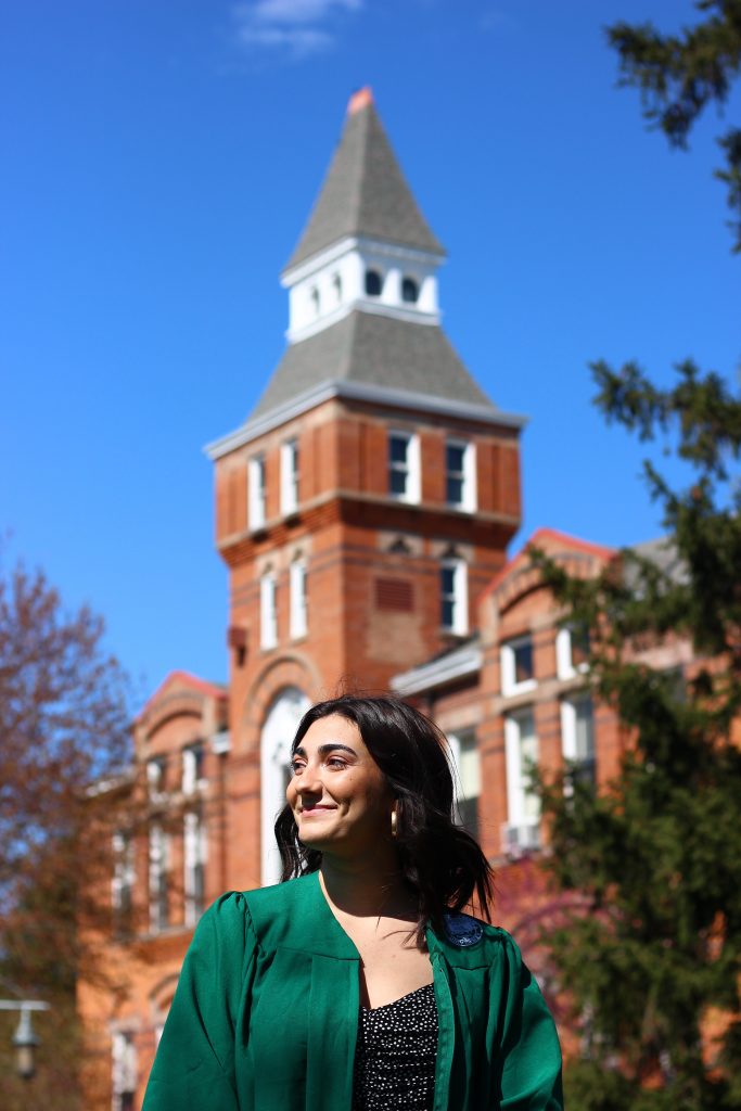 a girl standing in front of a brick building wearing a green gown